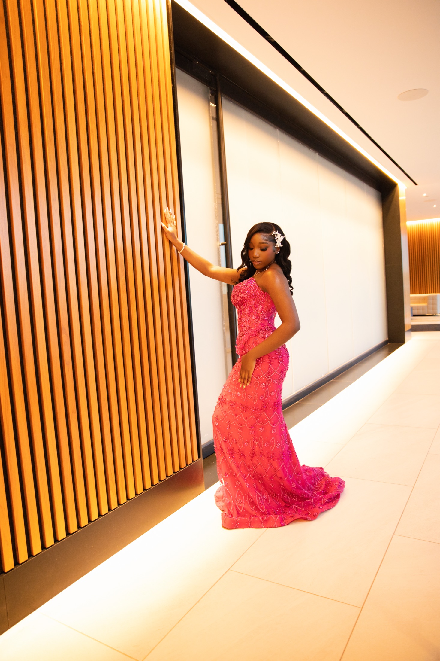 Formal portrait in pink gown beside wood feature wall